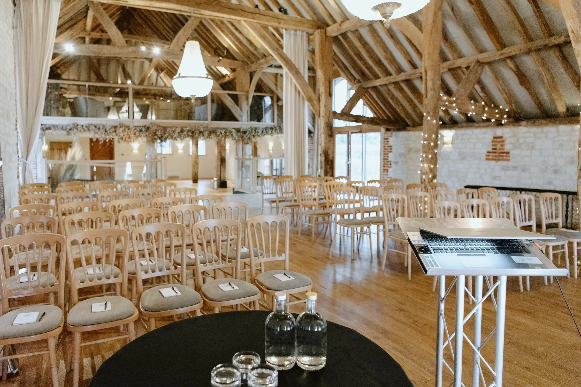 Theatre-style seating with notepads on each chair and a laptop lectern in the oak-framed barn