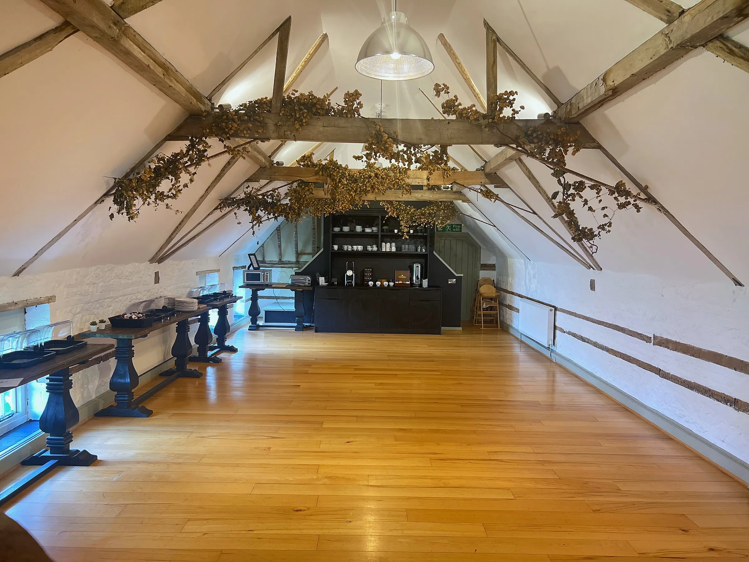 The Loft, a long white room under exposed roof timbers with an oak floor and a bar at the far end