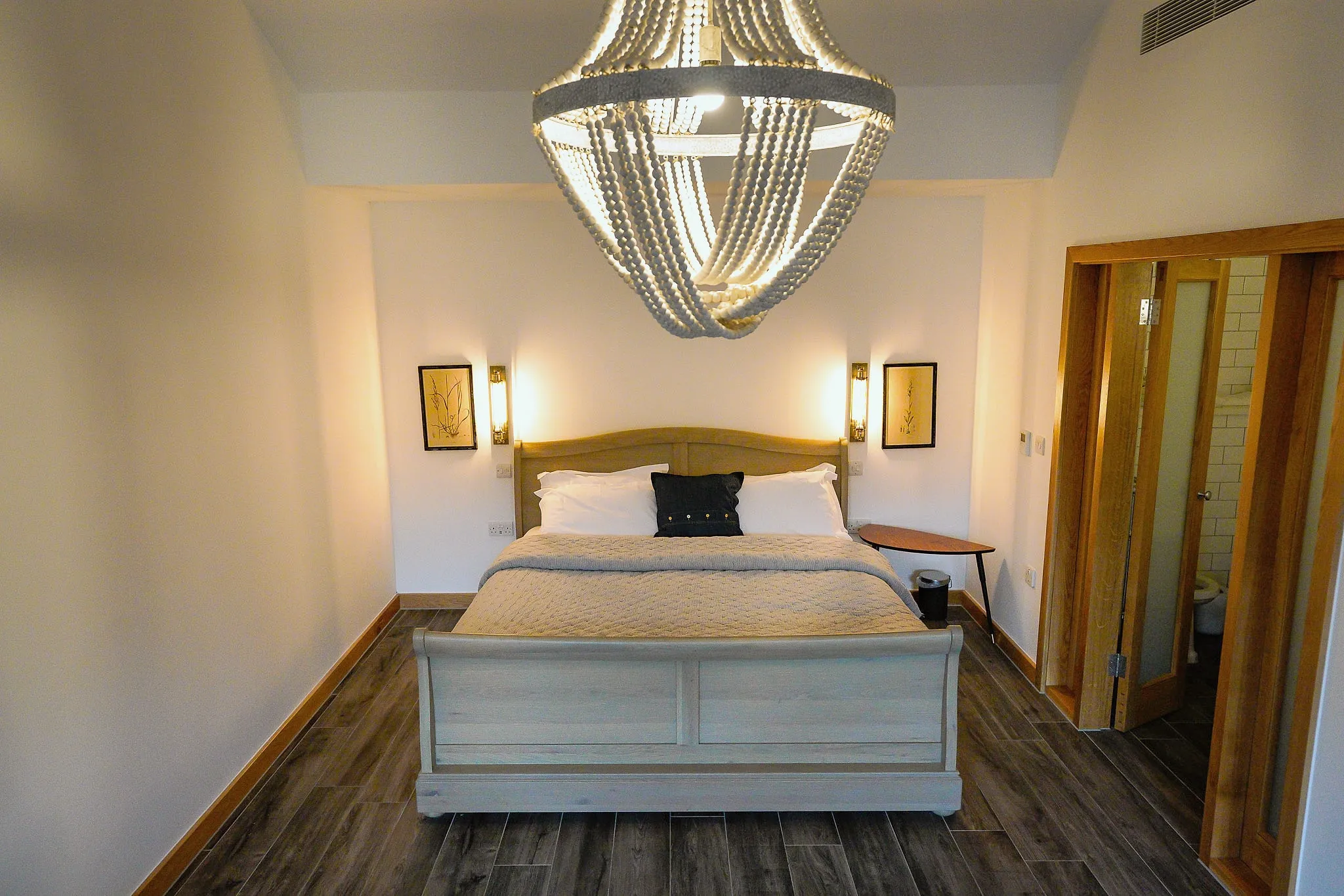 Calm double bedroom with a painted sleigh bed, wall lights and a beaded chandelier